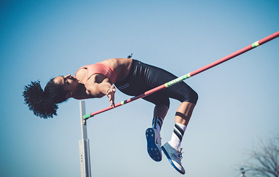 Woman completing high jump to promote leading athletics insurance broker Full-time Cover