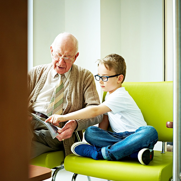 Granddad sharing magazine with grandson to promote health and life insurance broker Full-time Cover
