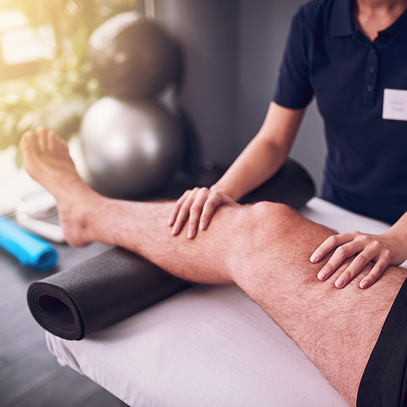 Male leg being tended to in physiotherapy session to promote Full Time Cover's Sports Accident Insurance