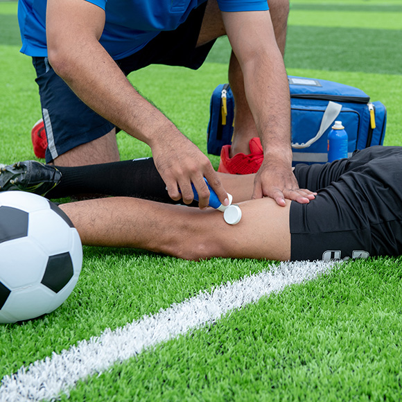 Male leg being tended to on football pitch to promote Full Time Cover's Sports Accident Insurance
