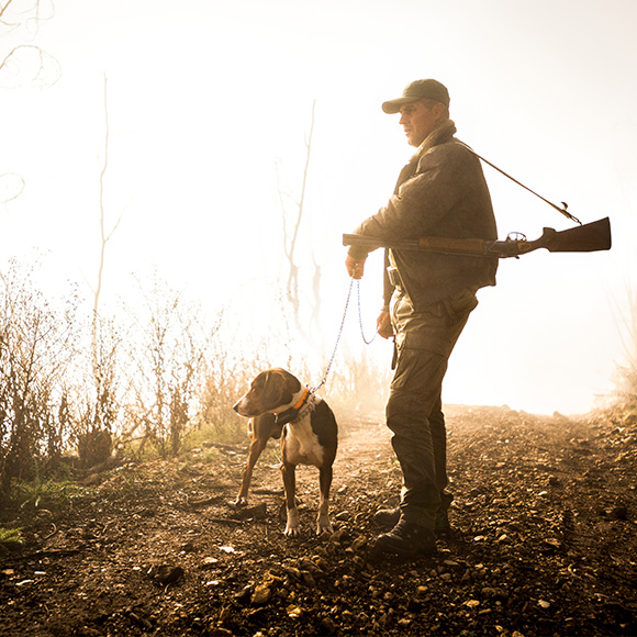Male walking in field with gundog to promote Full Time Cover's Sports Shooting Insurance