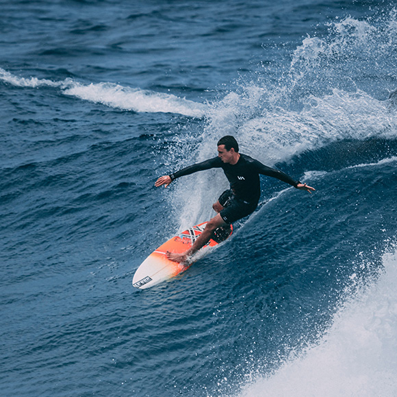 Male riding a wave while surfing to promote Full Time Cover's Sports Travel Insurance