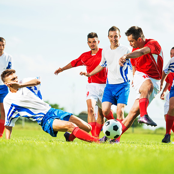 Multiple footballers going for the ball mid to promote Full Time Cover's Team Personal AccidentInsurance
