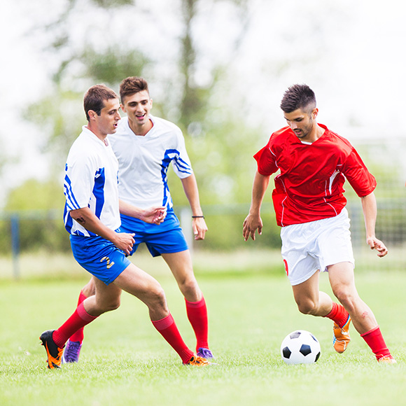Multiple footballers going for the ball mid game to promote Full Time Cover's Team Personal Accident Insurance