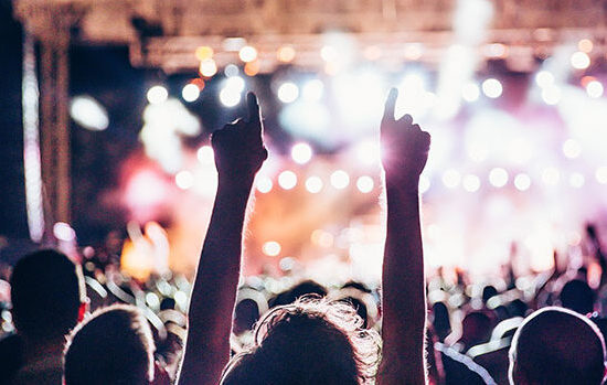 Excited fans raising their arms at a concert to promote Full Time Cover Insurance Brokers