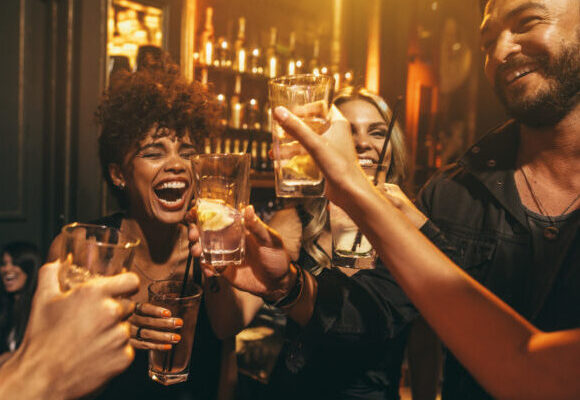 Shot of young men and women enjoying a party. Group of friends having drinks at nightclub.